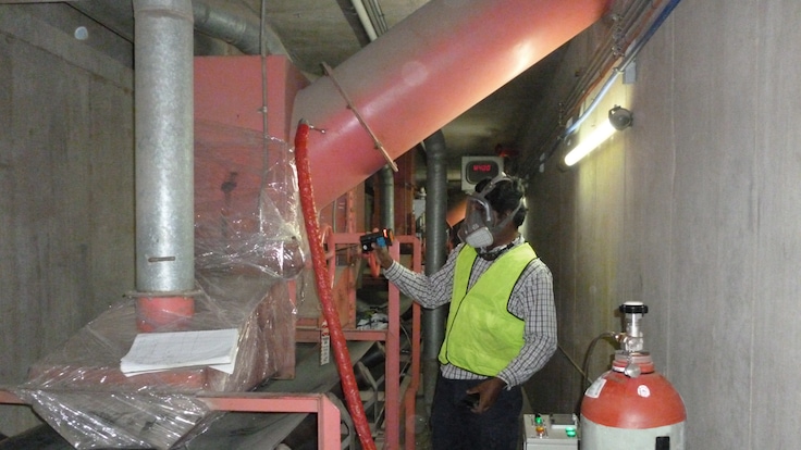 An operator dressed in PPE carries out a fumigation in an enclosed space. 