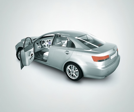 A silver saloon car with an open front left door taken from a rear side angle against a gradient grey background.