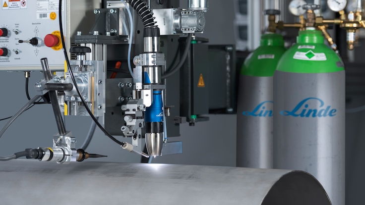A plasma arc welding system setup in a welding lab. Weling torch in fioreground, gas supply cylinders in background.
