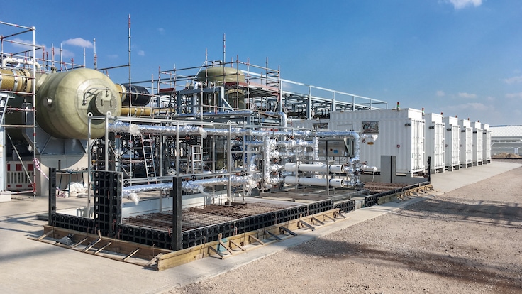 An on-site electrolyzer at Leuna power plant showing pipe network and six white container units.  